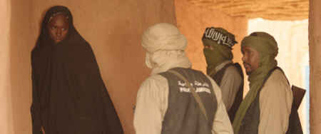 Man sieht in der linken Ecke ein Mädchen in schwarzer Burka, aber ihr Gesicht ist noch zu sehen, von rechts zingeln sie drei Männer ein, die mit Tüchern mehr oder weniger verschleiert sind und Waffen tragen.