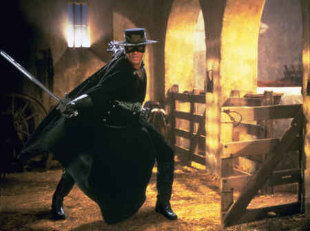 „Die Maske des Zorro“ im TV: Antonio Banderas in einem Stall mit schwarzer Maske, Hut, Kleidung und Umhang, wie er ein Schwert schwingt.
