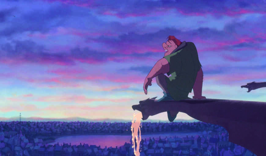 „Der Glöckner von Notre Dame“ im TV: Man sieht den buckligen Quasimodo auf einer Plattform Notre Dame sitzend, im Hintergrund liegt Paris, die Sonne geht gerade unter.